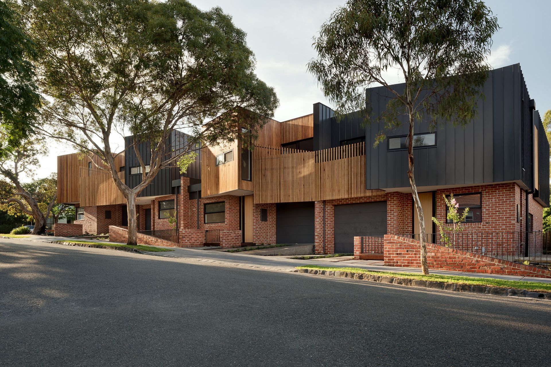 The exterior of these townhouses features a captivating blend of wood and brick. Photography by Emma Cross.