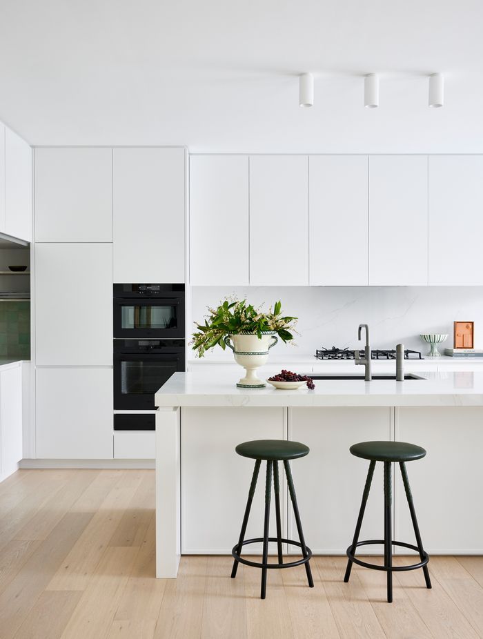 The kitchen and dining areas reflect the same refined minimalism seen throughout the home — warm timber, white joinery, and subtle textures.