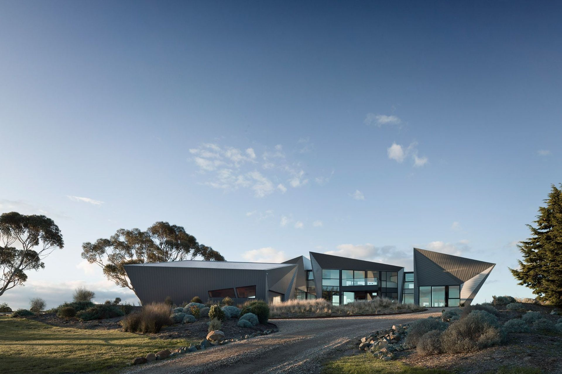The homes angular roofs and expansive windows bask in the soft glow of the morning light. Photography: Luke Butterfly