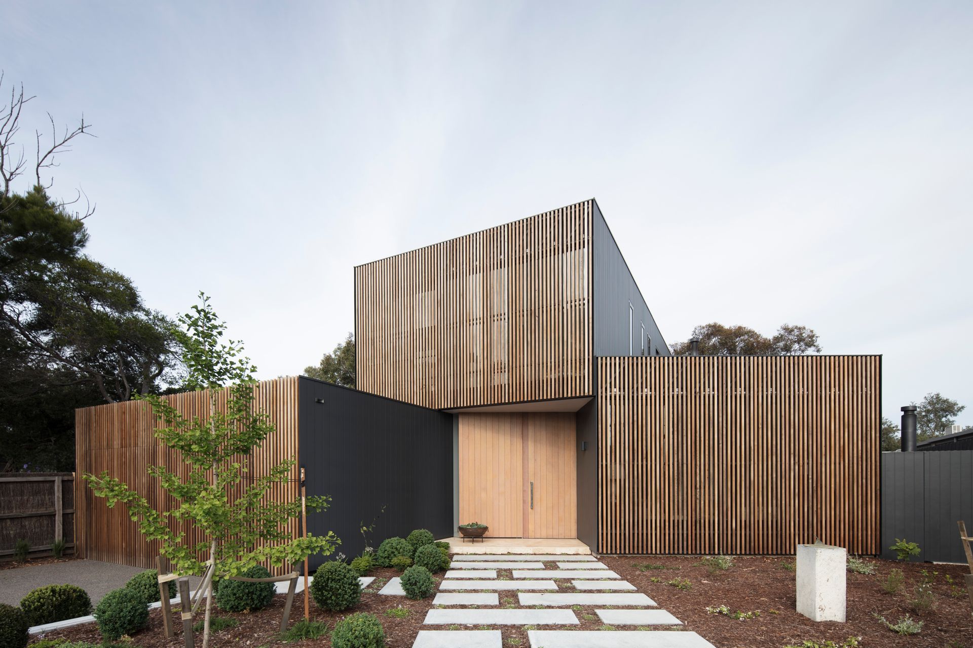 This home's facade mixing Western Red Cedar screens with a matte black metal finish creates a unique visual identity. Photography: Ben Hosking