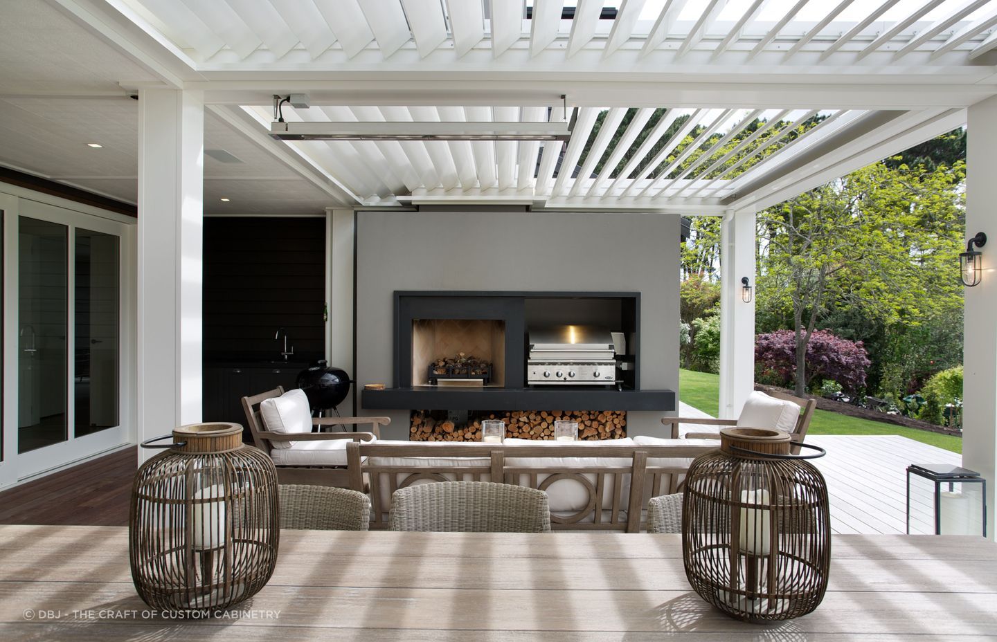 Trendy outdoor kitchen unit with additional décor truly raises the bar, courtesy of BJ — The Craft of Custom Cabinetry.