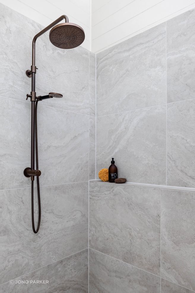 The Plumbline Shower Buddy Column in 'Aged Brass' contrasts with the textural tiles from Quantum.