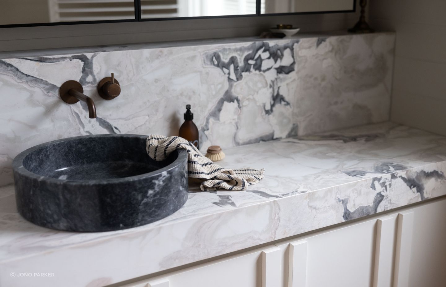 The Artedomus bluestone vessel basin contrasts with the lighter colours in the space, accentuating the marble's veining.