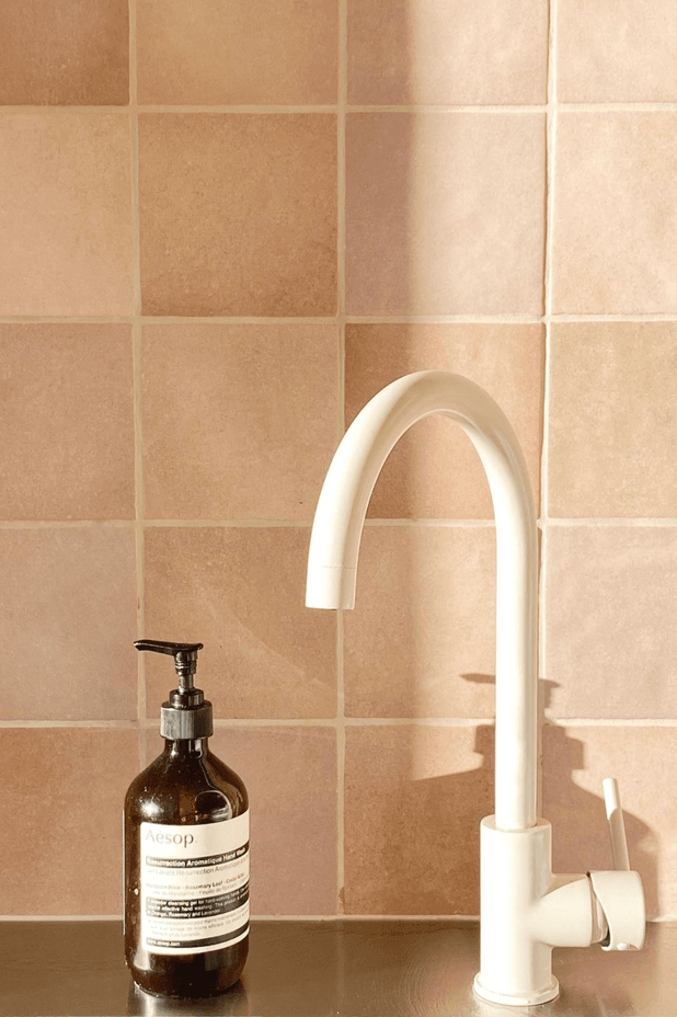 An ABI Interiors kitchen sink mixer in Almond pairs with the terracotta pink kitchen splashback.