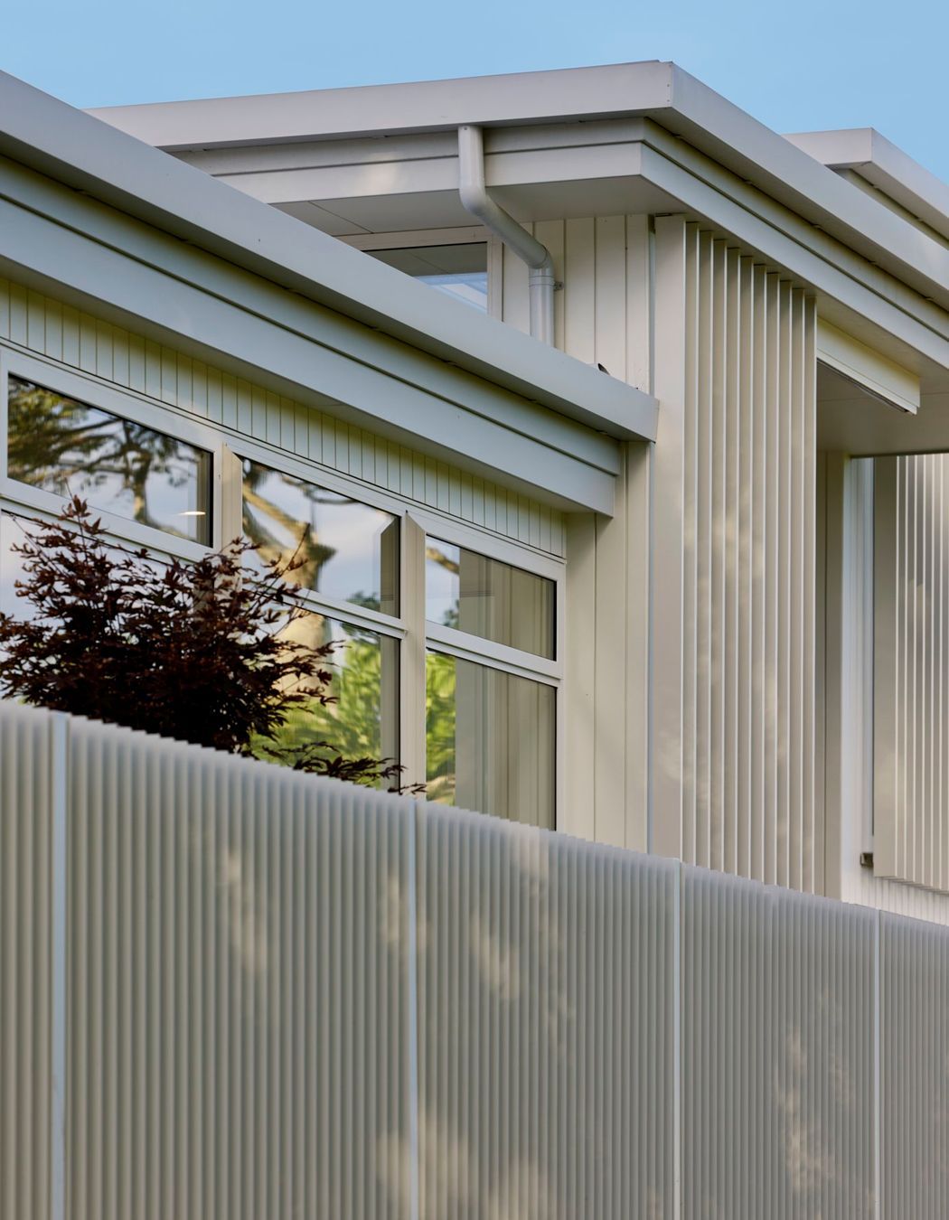 White-painted timber cladding reflects the coastal New Zealand architectural identity.