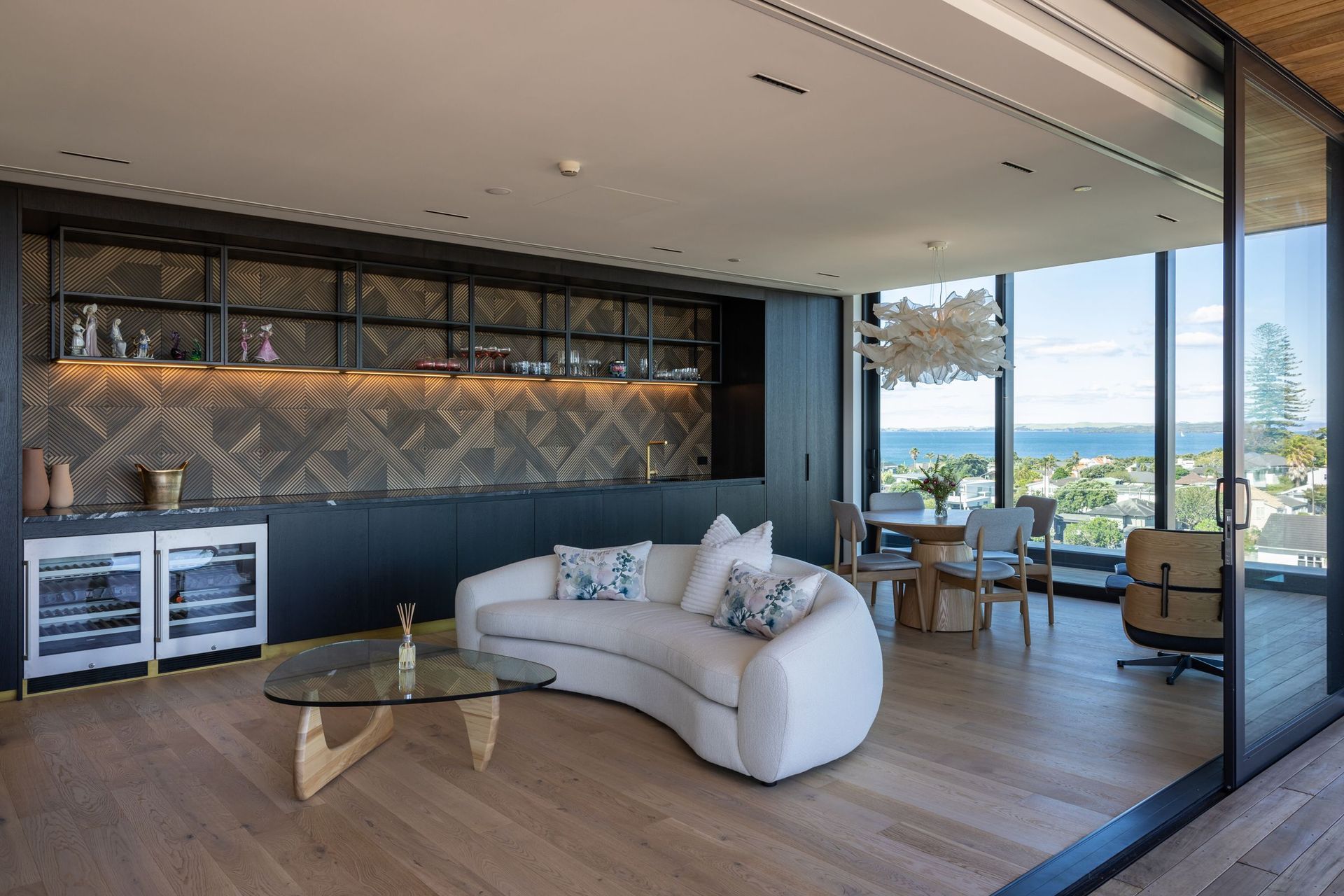 An entertainer’s dream, decking also extends from a second informal living space where a bar area impresses with its open shelving and woven-tiled splashback. 