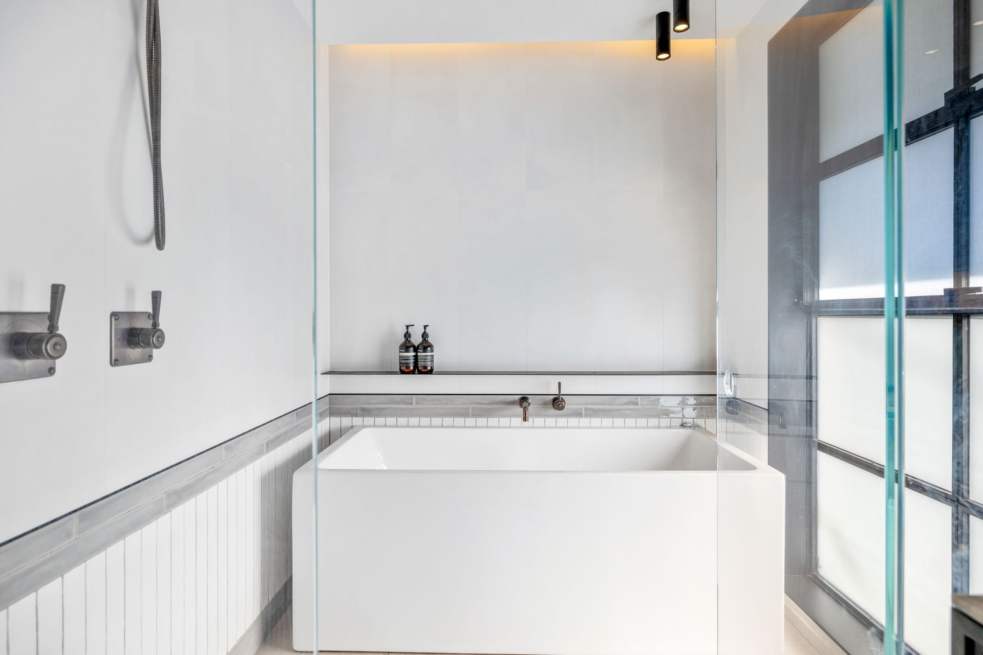 A family bathroom features handmade tiles soldiered around the base of the walls and a Japanese-style bath.