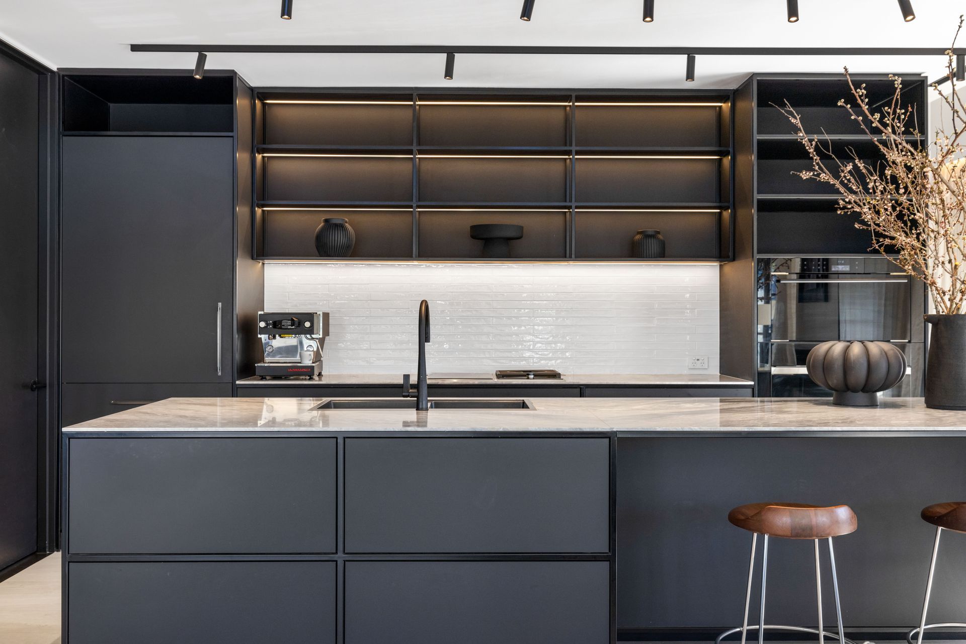 The monochromatic kitchen features black steel, tying beautifully with the steel joinery throughout the living space.