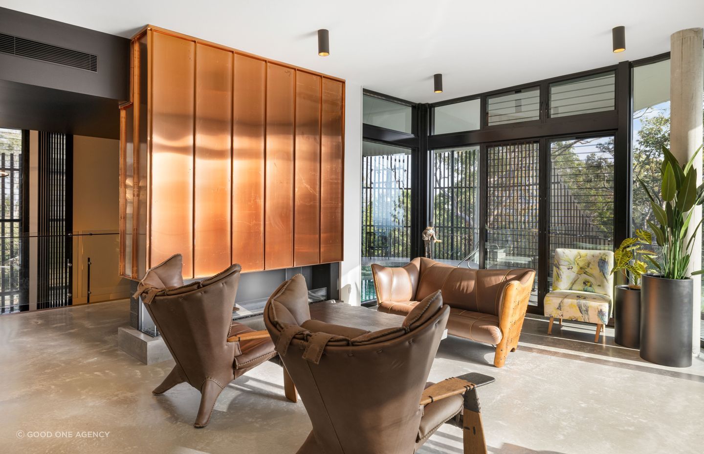 The double-height stairwell transitions directly into the main living space, which features a fireplace clad in copper.