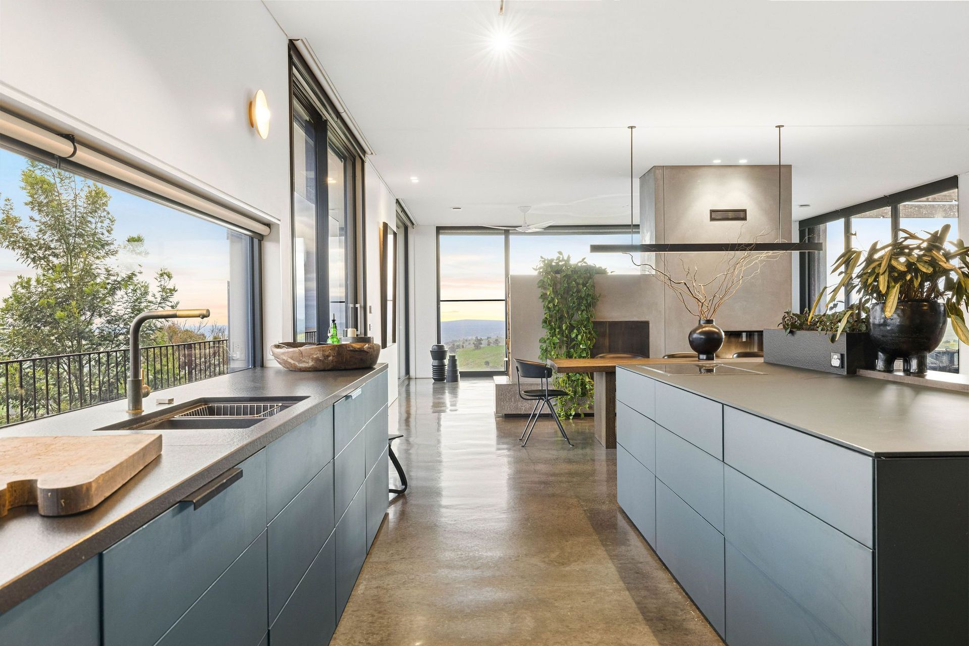 The home's petroleum-toned, glass kitchen creates warmth amid masses of floor-to-ceiling glass