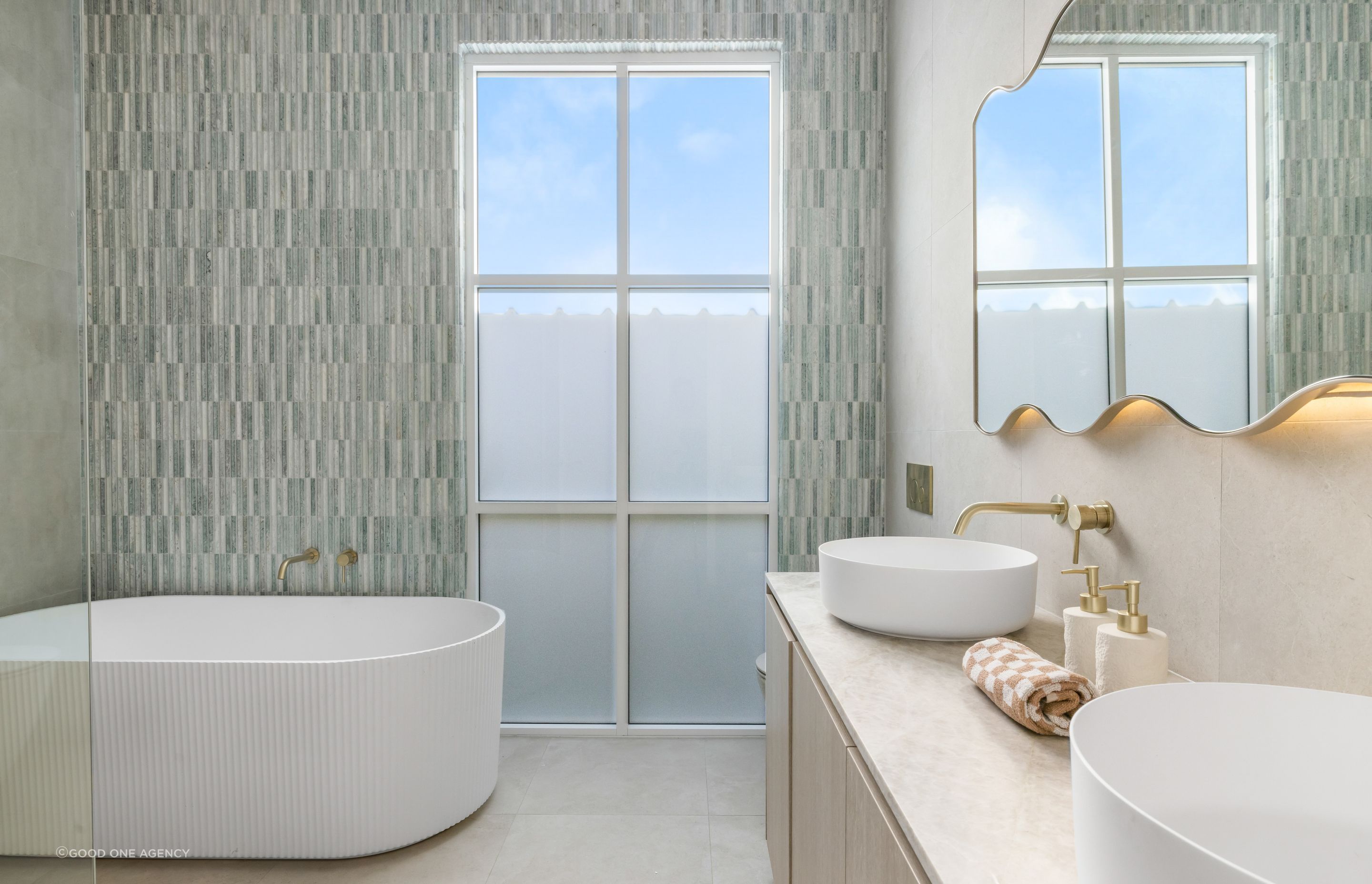 The main bathroom features a fluted porcelain tub and a pop of subtle colour in the green Moroccan tile feature wall.
