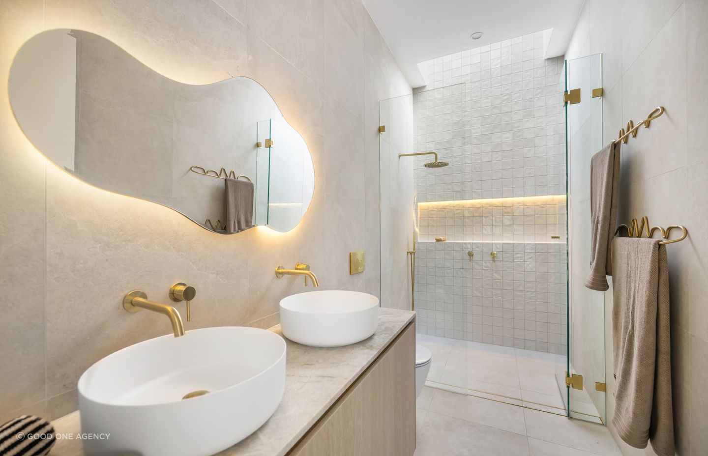 The master ensuite features brass accents against subtle tiling.