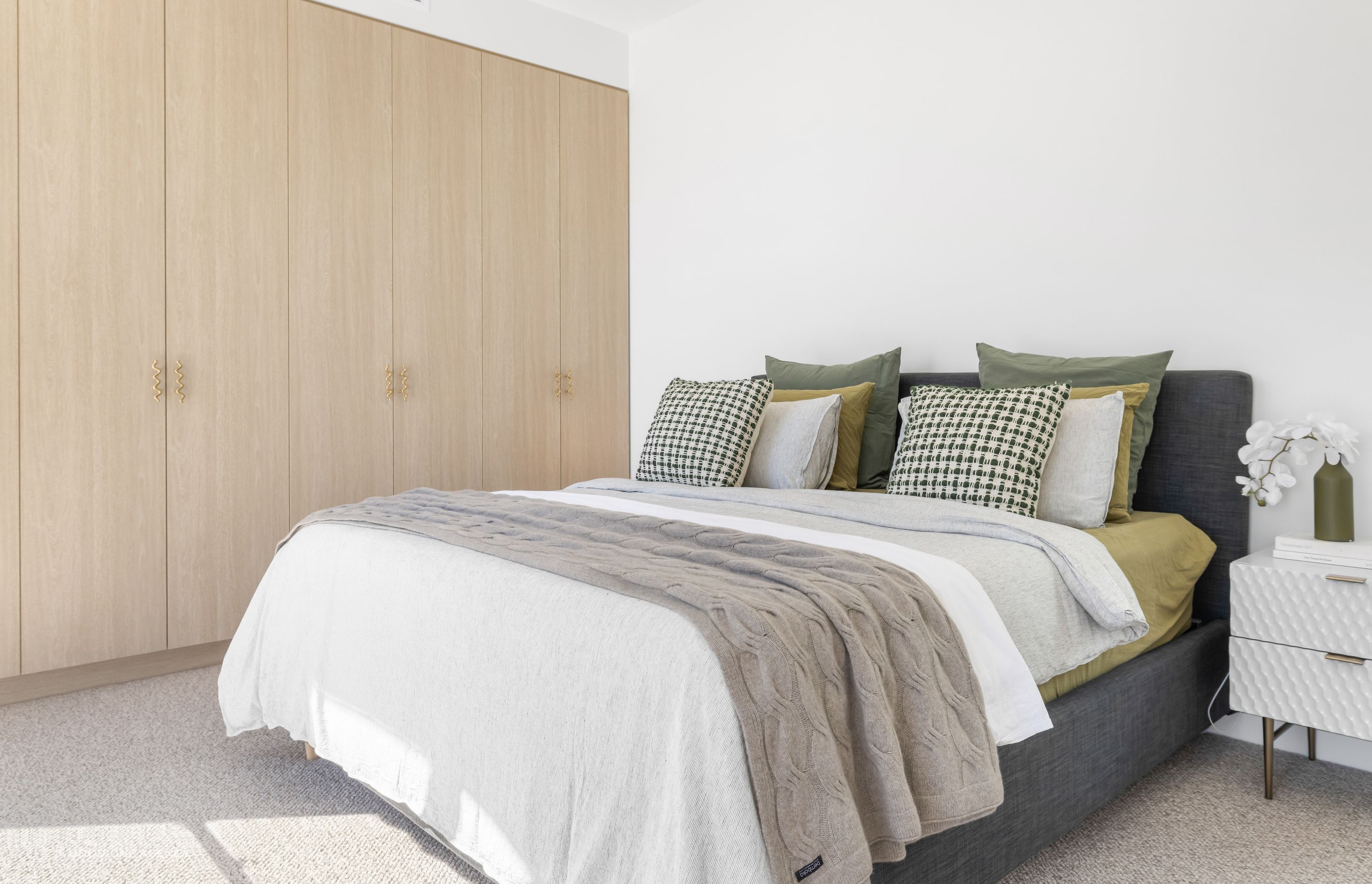 The master bedroom features a soft material palette and the playful squiggle handles that are found throughout the home.