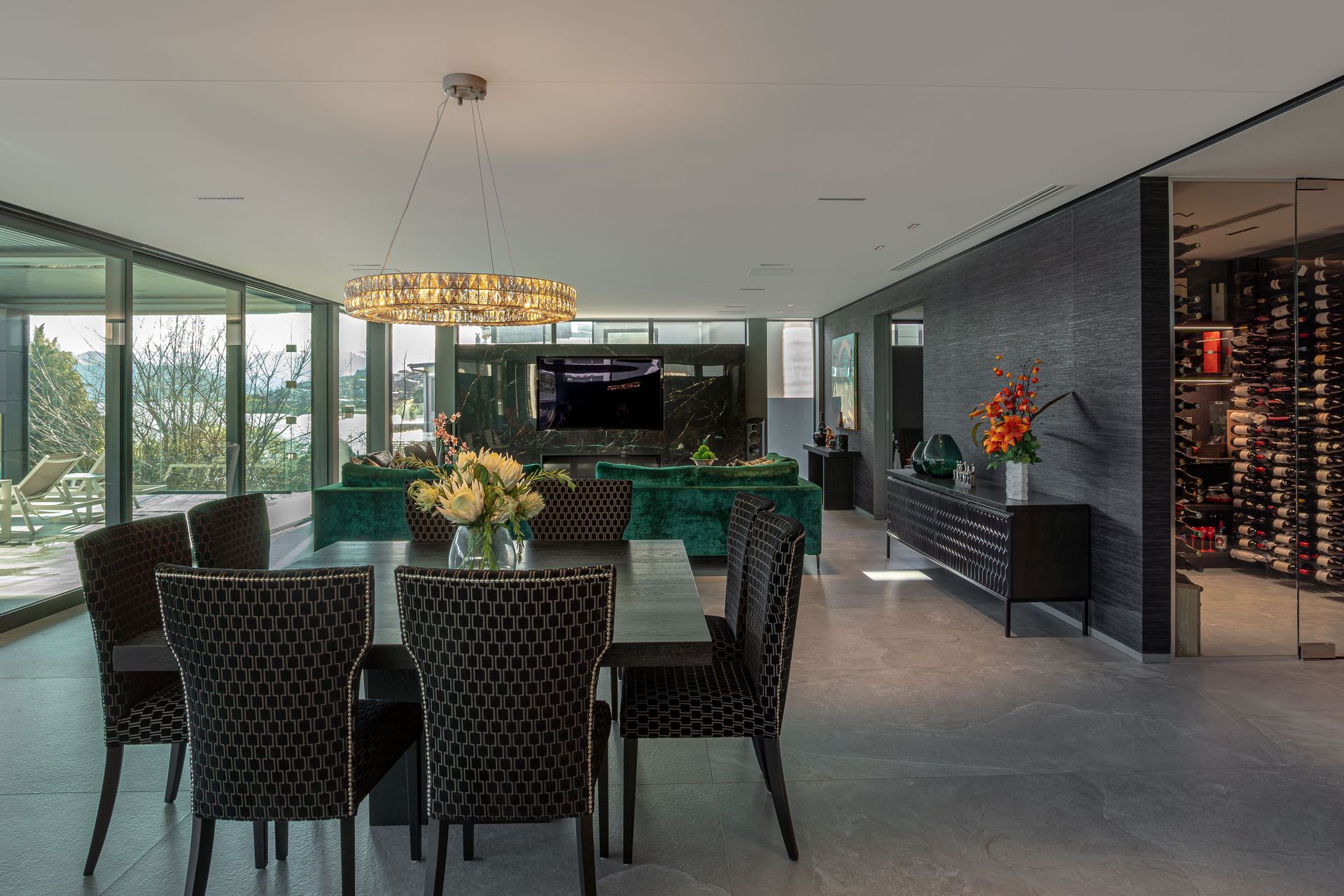 Descending from the foyer, the home expands into a dramatic, open living, kitchen, and dining space complete with a pantry and wine cellar.
