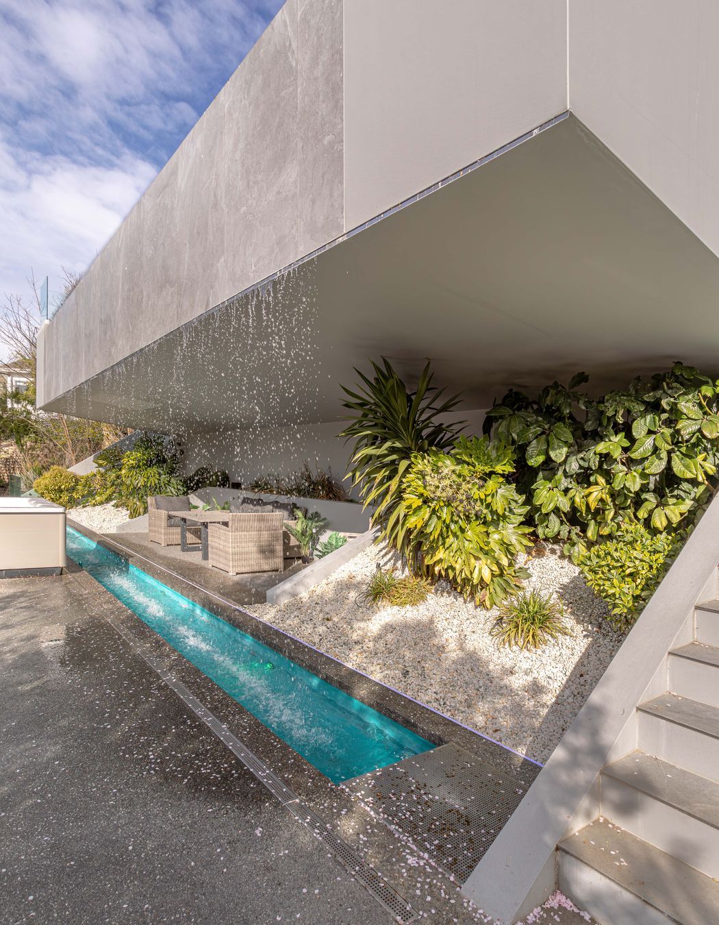 An intimate grotto is recessed behind the waterfall's downpour, complemented by lush foliage.