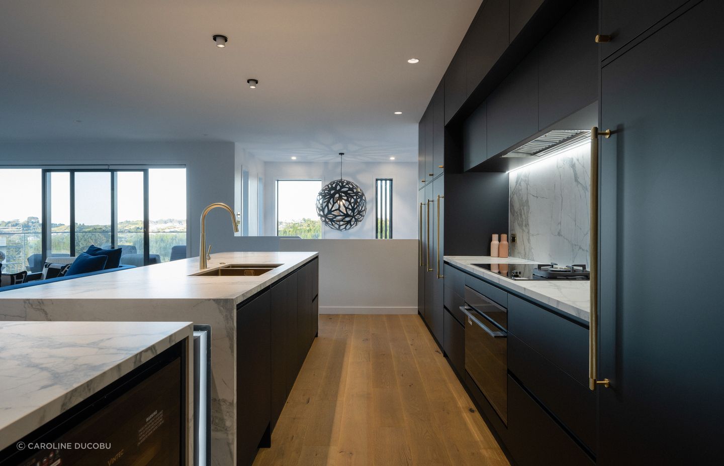 A contrast to the porcelain bench, the kitchen cabinetry is sleek in black – contrasting also with the brass handles. 