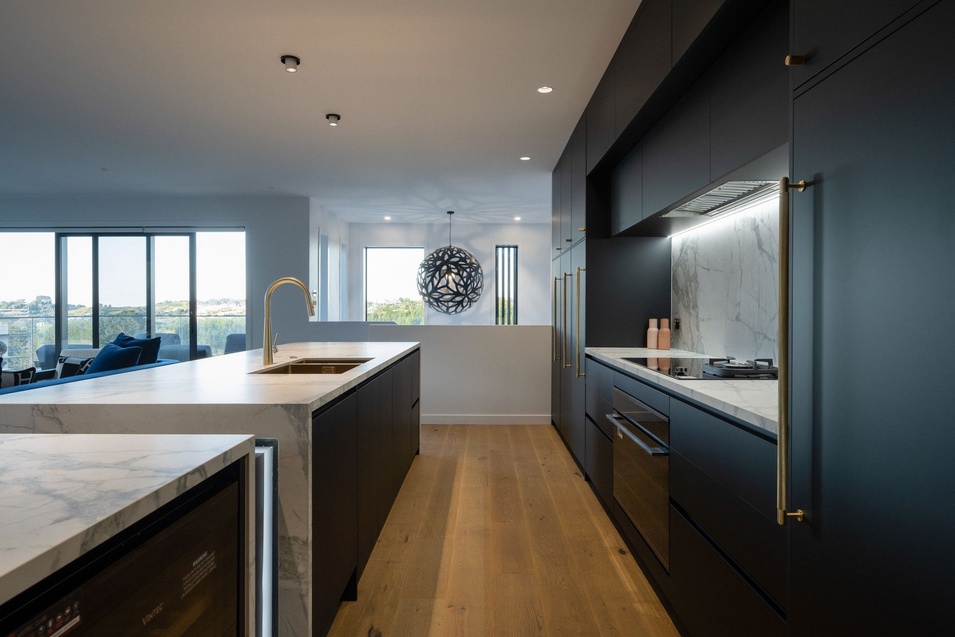 A contrast to the porcelain bench, the kitchen cabinetry is sleek in black – contrasting also with the brass handles. 