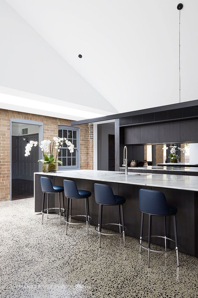 The kitchen features dramatic dark cabinetry that contrasts against the stone benchtop.