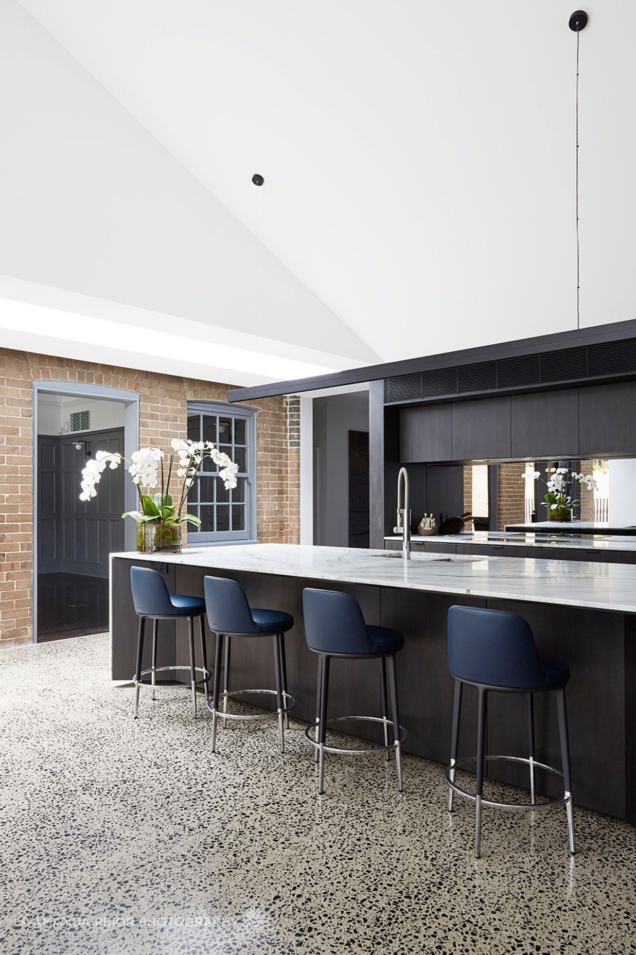 The kitchen features dramatic dark cabinetry that contrasts against the stone benchtop.