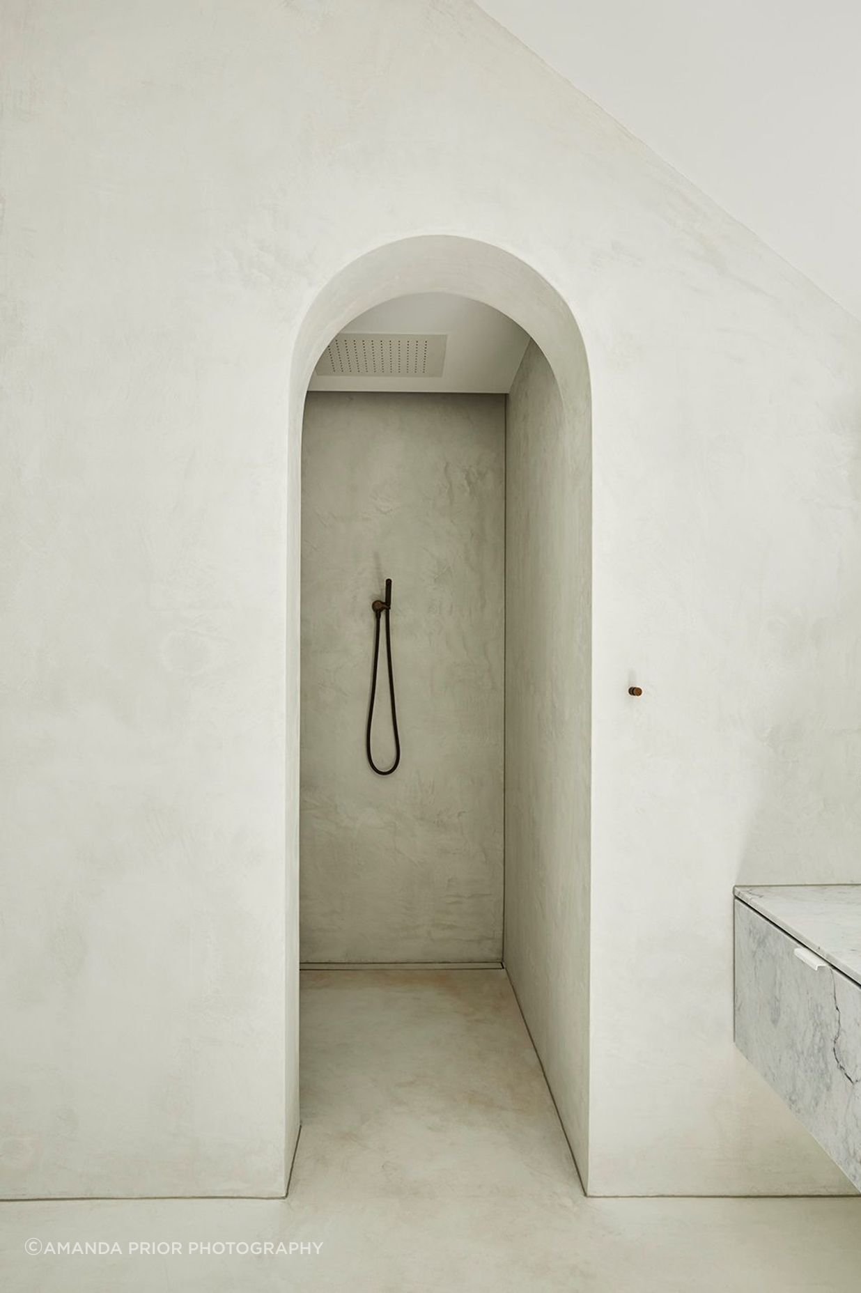 An archway entry adds drama to the master walk-in shower.