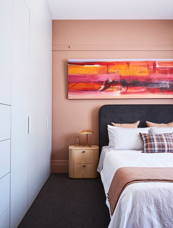 In a bedroom, a pop of pink uplifts and integrates the artwork