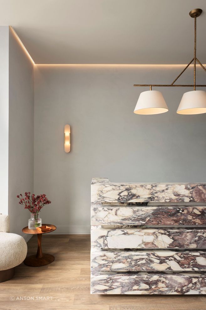 The sculptural form of the reception desk anchors the space, creating a sense of drama and presence.