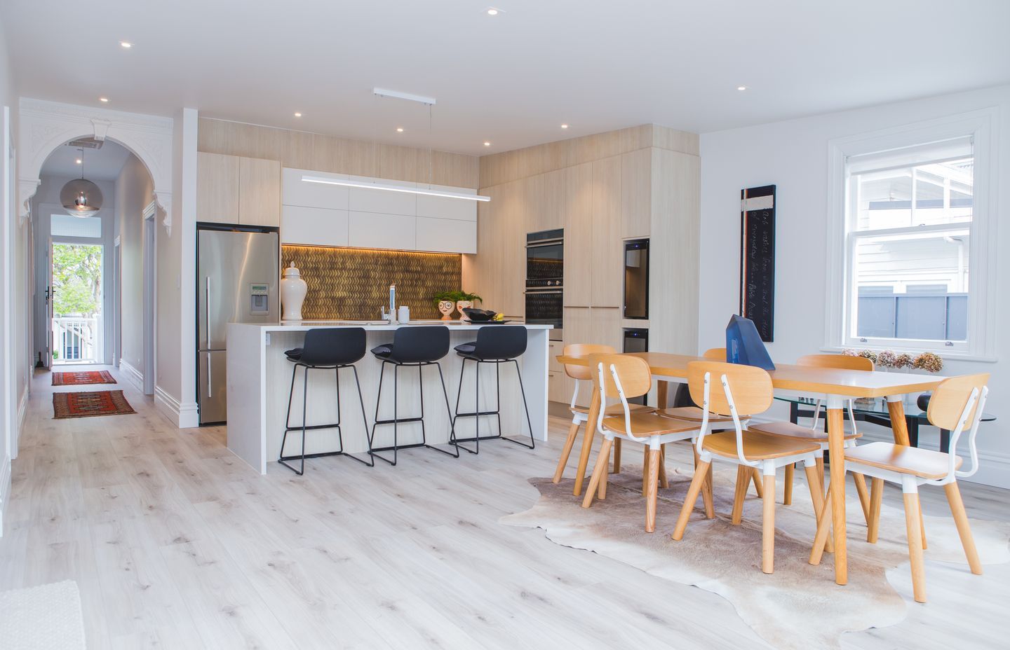 The open-plan kitchen and dining area is found beyond the hallway arch which defines the existing floorpan from the addition. The renovation also involved the installation of Autex Greenstuf to insulate the home.