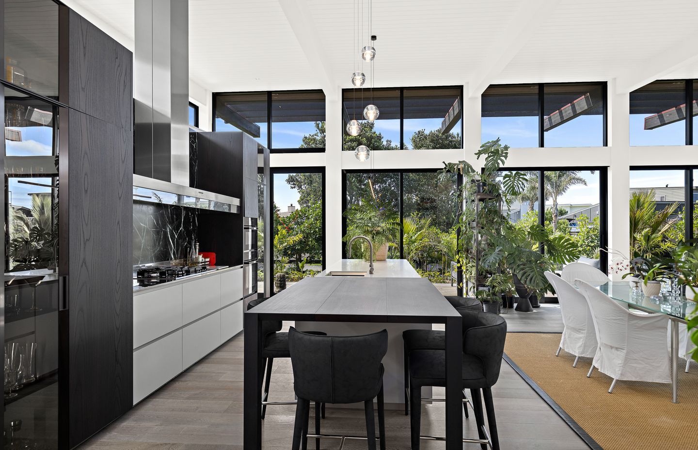 Dark wood veneer kitchen cabinetry supplied and installed by Studio Italia complements the home’s exterior – contrasting with the Pumice French oak flooring from Artedomus. A Bocci 5 pendant from ECC lighting is suspended above the island bench.