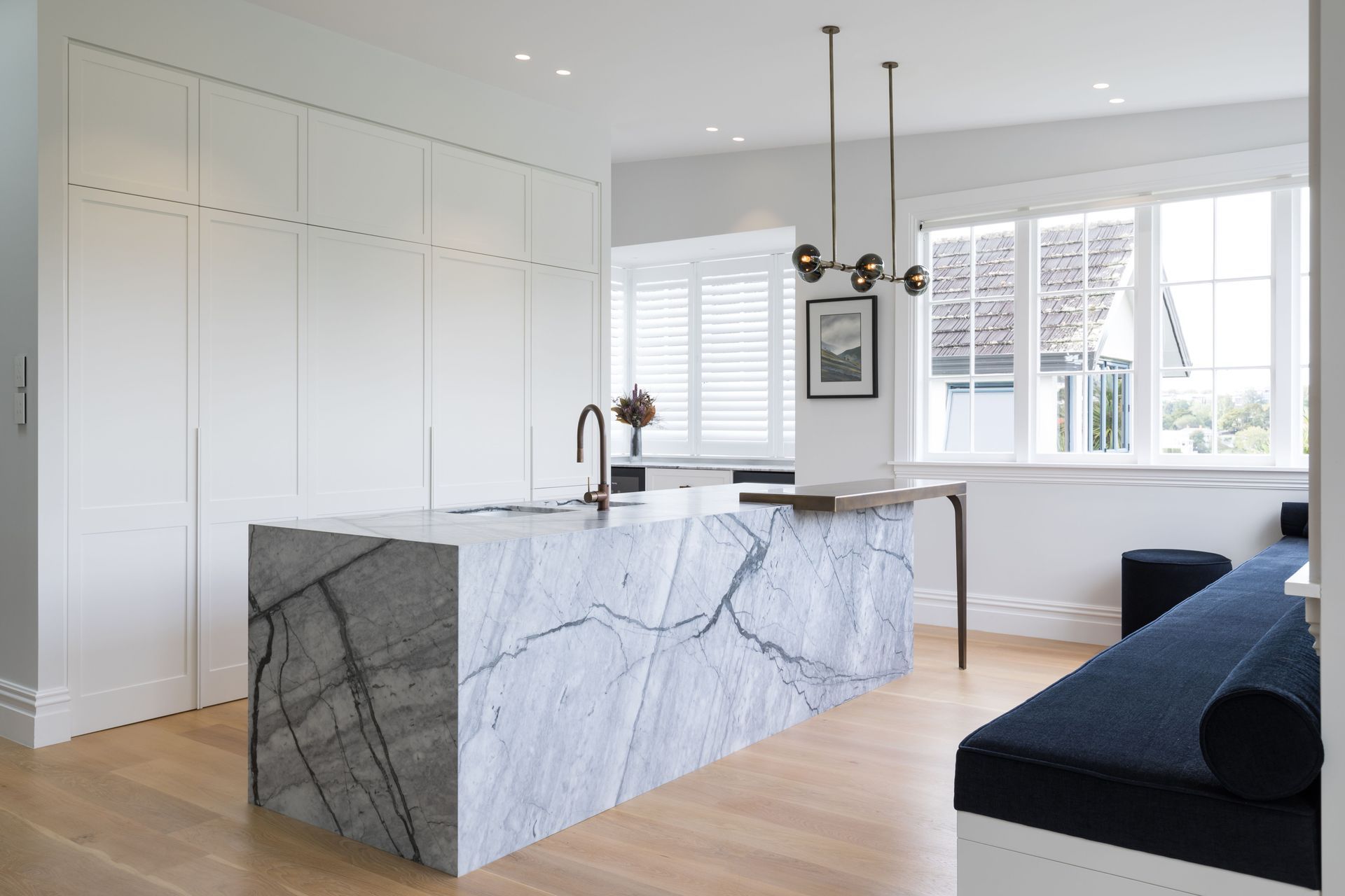 With the hob area doors closed, the island becomes the centrepiece says Sticks + Stones Design interior designer Katie Scott. The white in the walls and cabinetry is Resene Half Sea Fog.