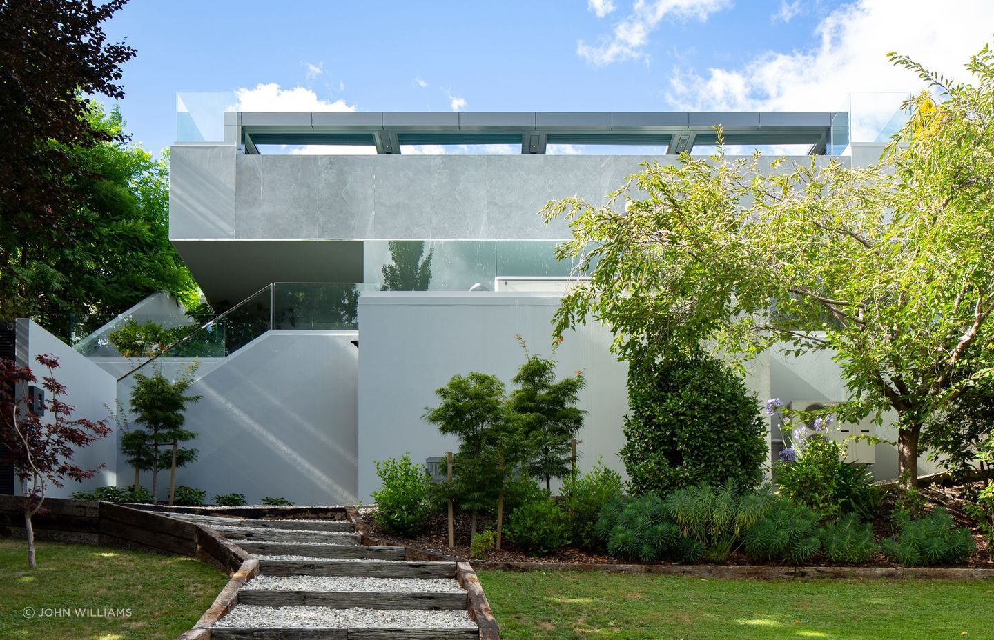 The lowest level is met by the deep greens of an established, landscaped garden and the rich blues of Lake Wakatipu.