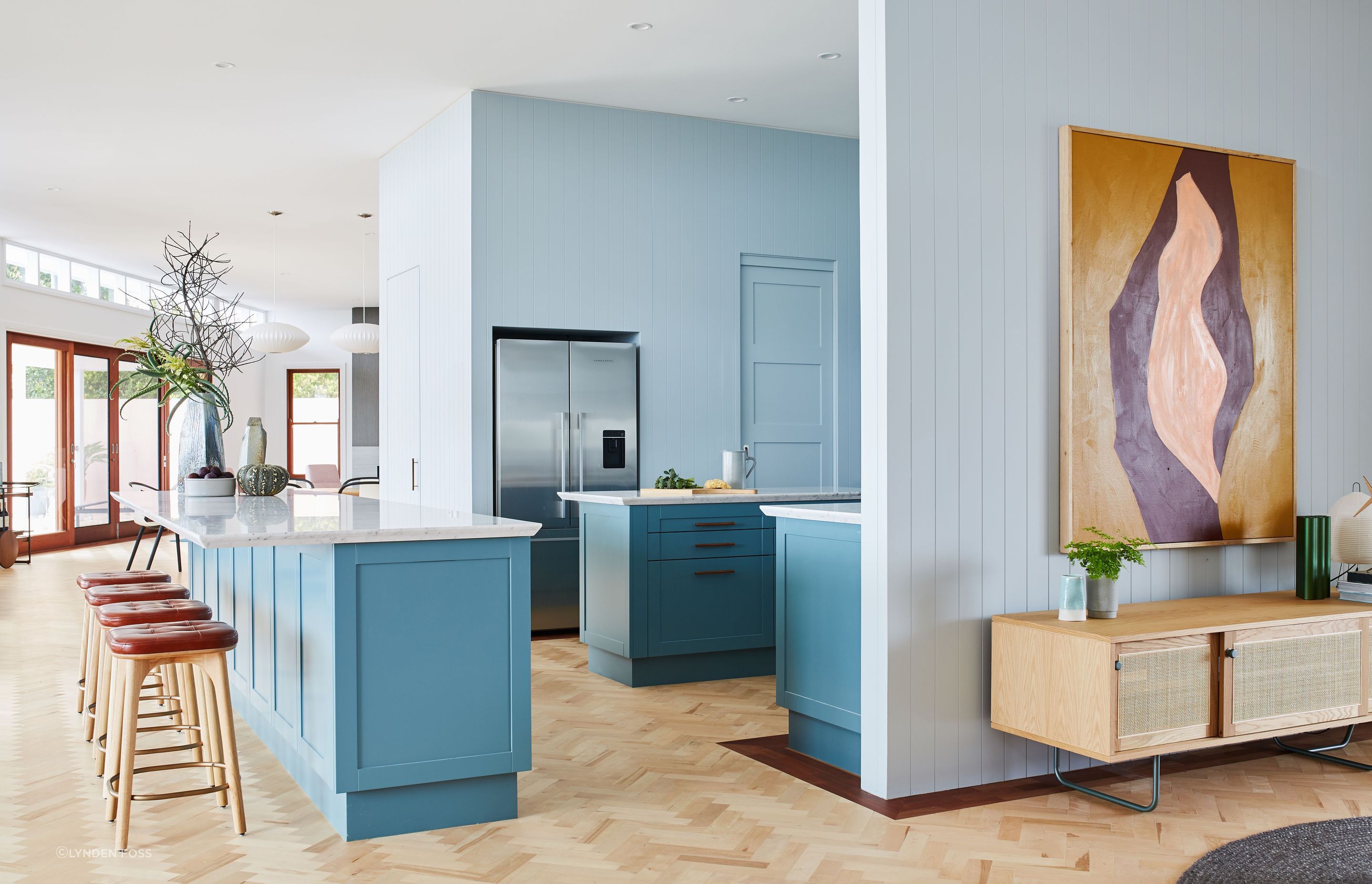 The soft dusty blue wraps around both sides of the kitchen walls and contrasts serenely with the teal cabinetry.