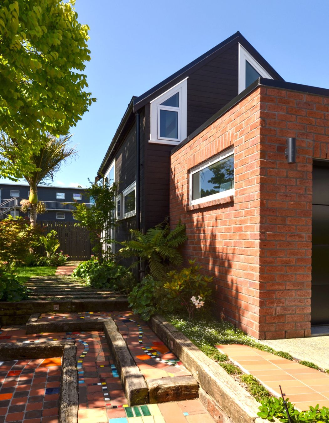The tiny home is tucked behind a brick-clad garage.