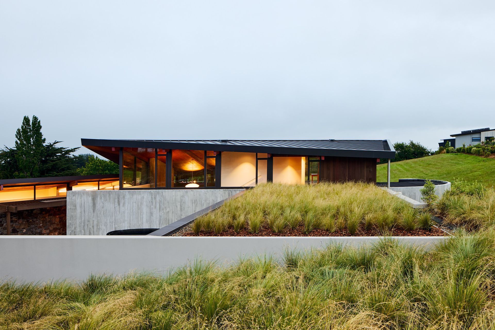 A three-car, half-buried garage is embedded into the hillside and topped with tussock. 