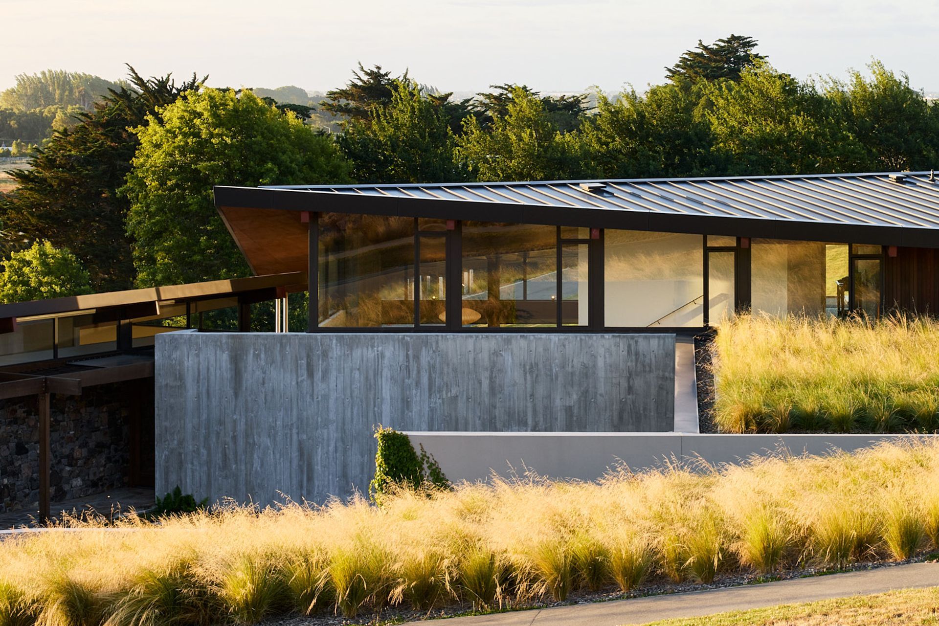 The home is embedded into the gently sloping site, anchored by heavy materials.