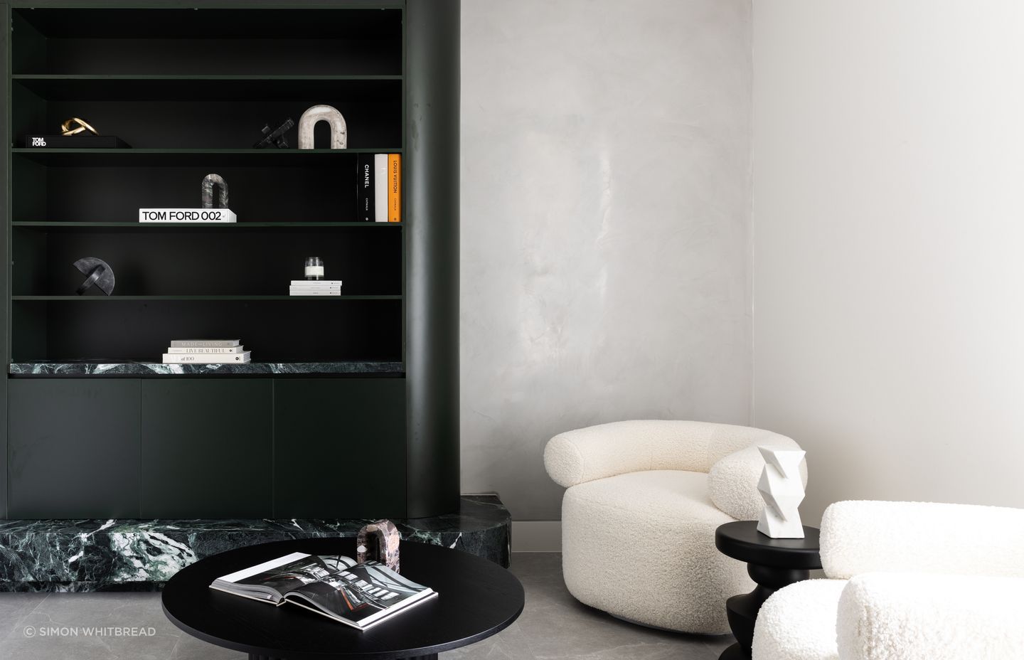 Dark green cabinetry and stone contrast with light Venetian plaster in the reading area.