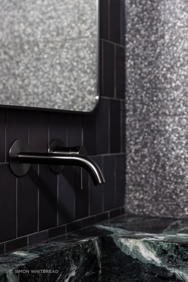 The natural green stone takes centre stage in front of the black tiles.