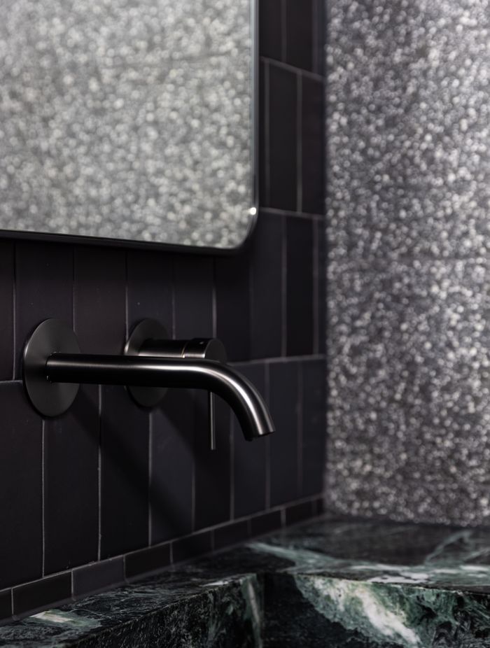 The natural green stone takes centre stage in front of the black tiles.