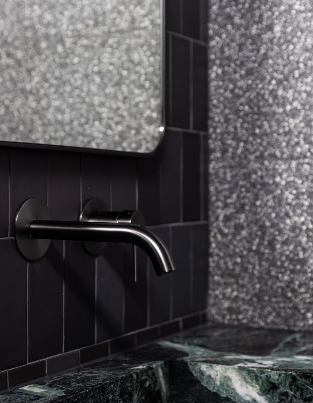 The natural green stone takes centre stage in front of the black tiles.