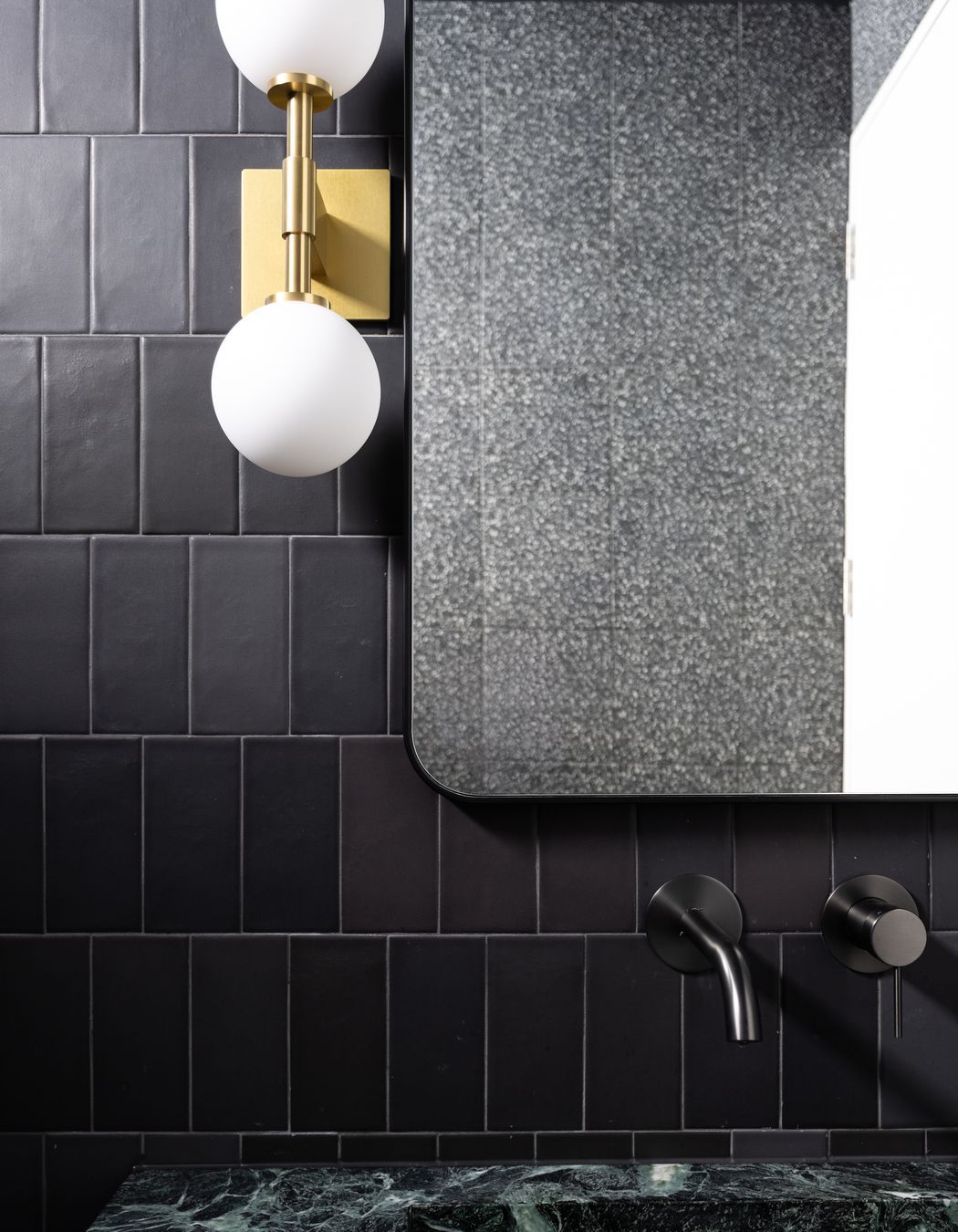 The brass wall light from Allied Maker is a luxurious touch to the bathroom.