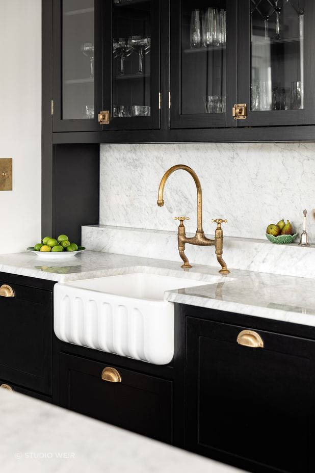 Brass hardware beautifully accents the black kitchen cabinetry.