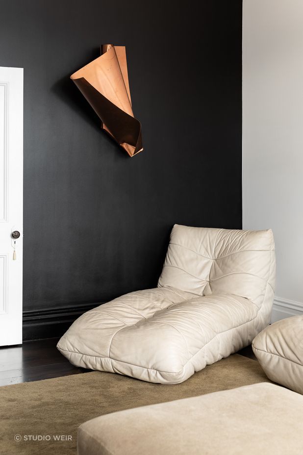 The black wall has been refinished and serves as the perfect canvas for the family's growing art collection. The chair is Babelogue and the rug is from Simon James.