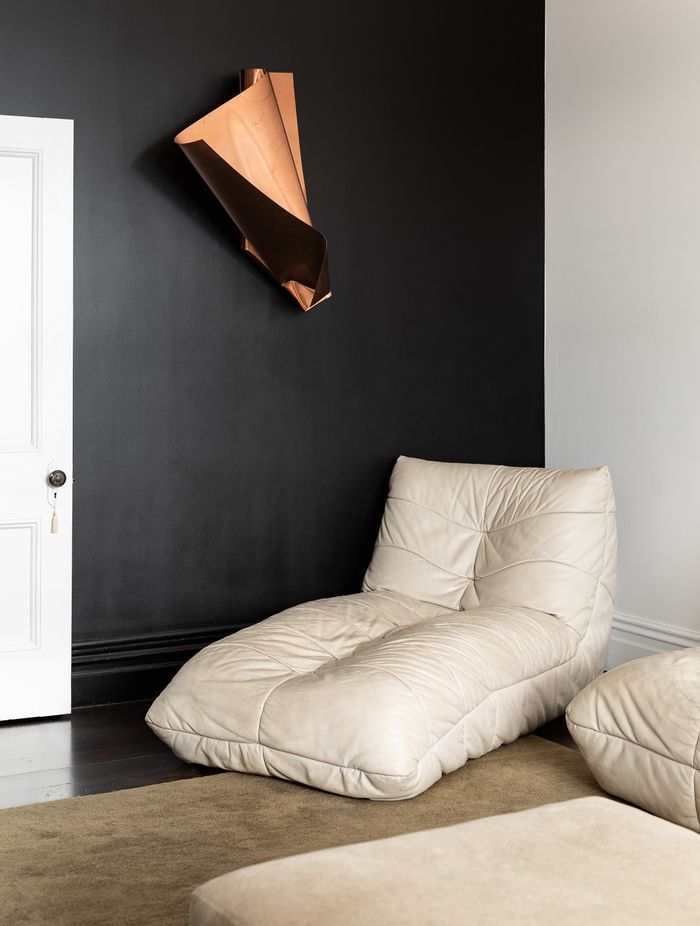 The black wall has been refinished and serves as the perfect canvas for the family's growing art collection. The chair is Babelogue and the rug is from Simon James.