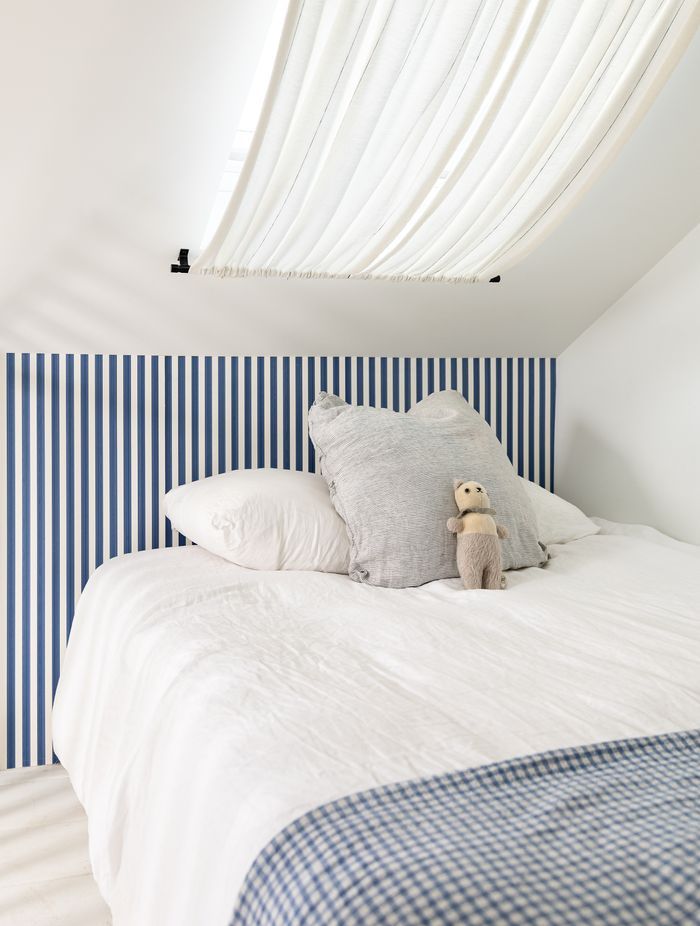 The blue-striped Farrow &amp; Ball wallpaper brings a fun sailor's theme to the bedroom.