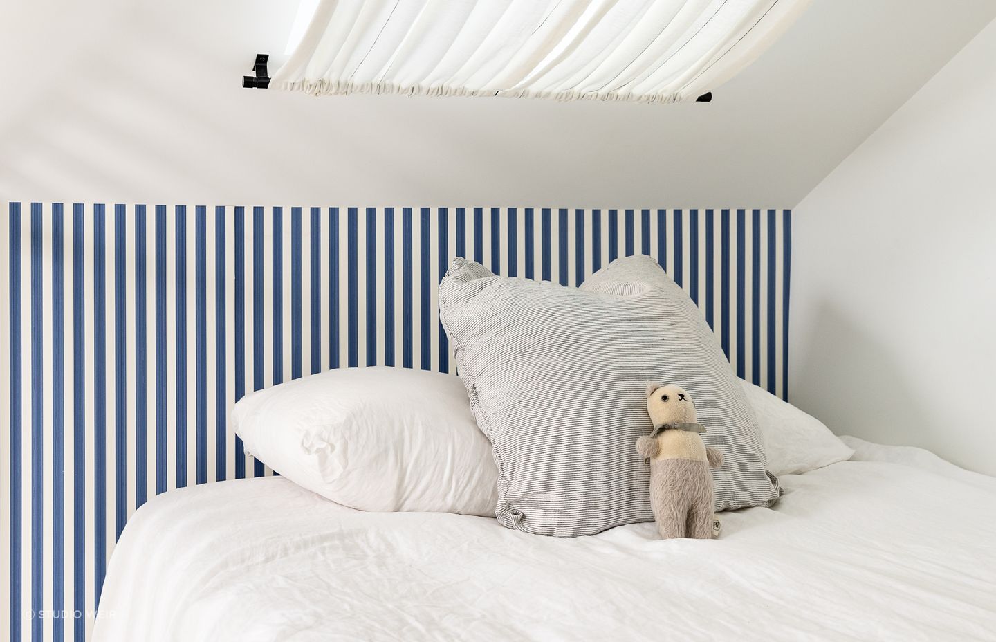 The blue-striped Farrow &amp; Ball wallpaper brings a fun sailor's theme to the bedroom.