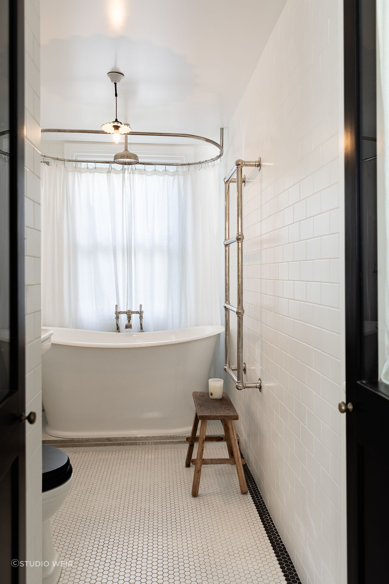 The children's bathroom features traditional butcher wall tiles and a bath from In Residence. The shower curtain ring is bespoke by Buxeda Construction.