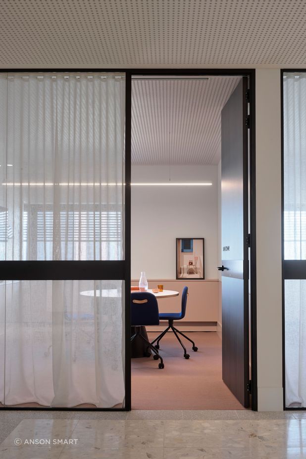 A meeting room is softened with pastel colours, sheer curtains and beautiful photographic art.