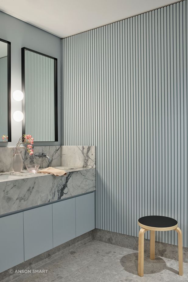 The soft ribbing in the wall panelling contrasts against the marble vanity in the bathroom.