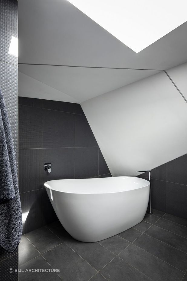 Free standing bath tub complemented by black floor tiles | Photography: Tom Ferguson