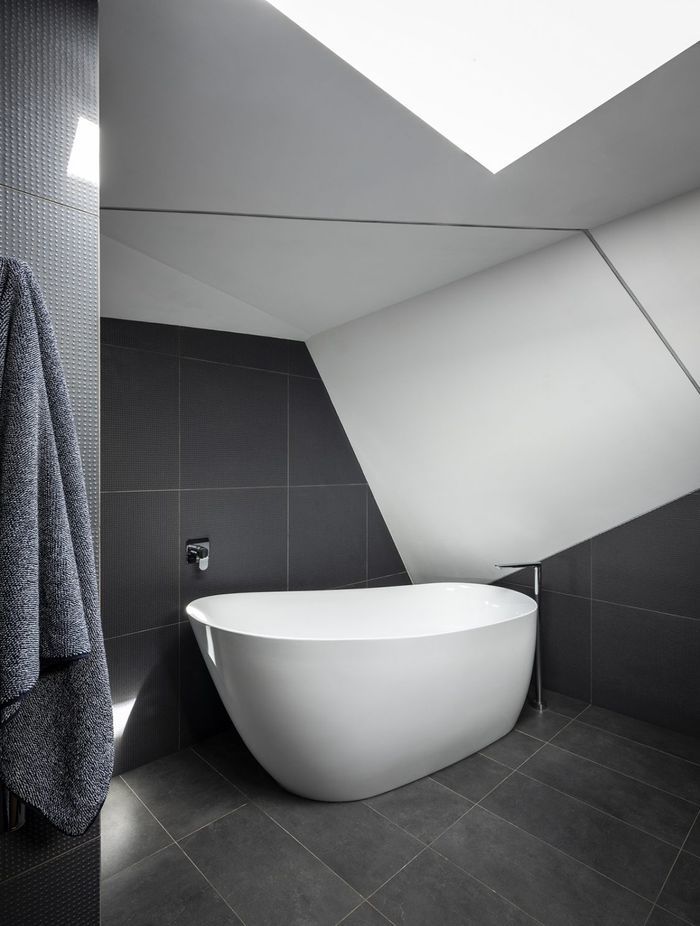Free standing bath tub complemented by black floor tiles | Photography: Tom Ferguson