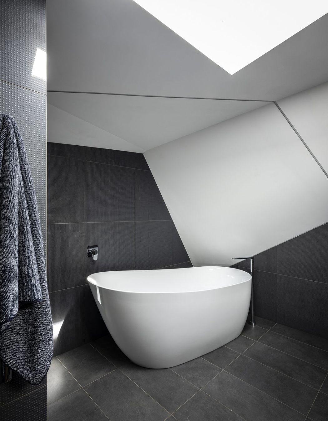 Free standing bath tub complemented by black floor tiles | Photography: Tom Ferguson